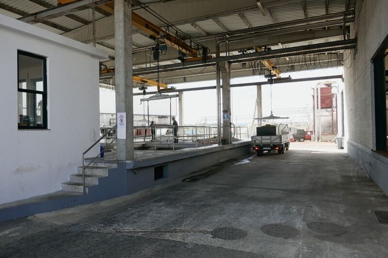 DC 22-0808-029.jpg :: Saga Douro River Cruise, Favaios:  The building in the image is the Adega Cooperativa de Favaios, a renowned winery located in the village of Favaios within the Douro wine region of Portugal. The winery is famous for producing one of Portugal's most iconic fortified wines, Moscatel de Favaios. The winery is nestled in the picturesque Alto Douro wine region of Portugal, a UNESCO World Heritage site. Founded in 1952, the cooperative was established by local producers to create their famous Moscatel wine. While most famous for its Moscatel, the winery also produces DOC Douro wines (white, red, and rosé), sparkling wines, and Port wine. Unloading bays. Photo taken 02/09/2022