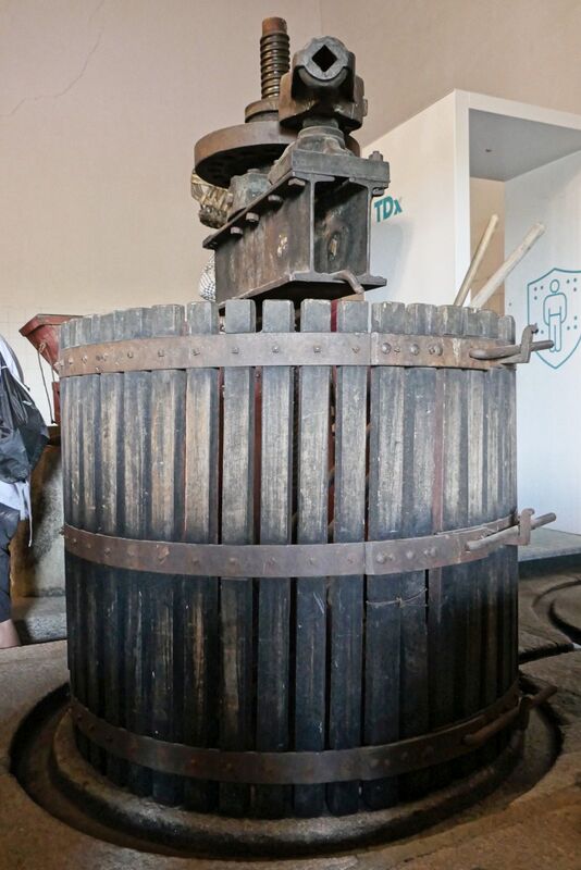 DC 22-0808-068.jpg :: Saga Douro River Cruise, Favaios, Avessada Wine Estate: Quinta da Avessada is located in the centre of the Douro demarcated region at its highest point (at an altitude of 600 meters) and the flattest point in the whole region (about 1,000ha of plateau), consisting of four buildings (one of them is one hundred years old) and 25ha of planting. Due to this, 90% of its plantation is destined to the production of Muscat grapes, with which Moscatel de Favaios is produced, and is designated a national apéritif. It is the Wine-Growing Village of Favaios. A traditional wooden basket wine press, a type of mechanical press used to extract juice from crushed grapes during winemaking. This design has been in use since the Middle Ages and is still popular among artisan and small wineries for its ability to produce high-quality, clear juice. Photo taken 02/09/2022