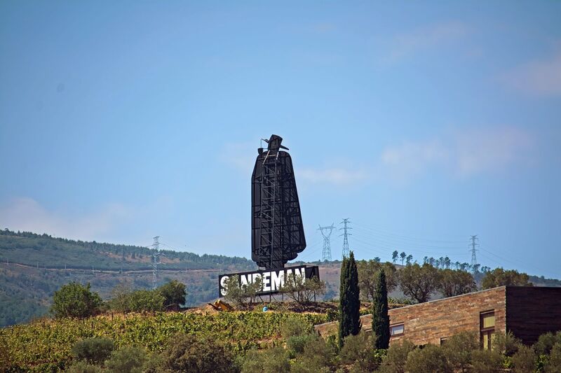DC 22-0809-004.jpg :: Saga Douro River Cruise, Pinhao to Regua, Portugal: The iconic Don Sandeman logo overlooking terraced vineyards in the Douro Valley, Portugal. This large-scale silhouette is a famous landmark in the region, specifically near the town of Peso da Régua. The \
