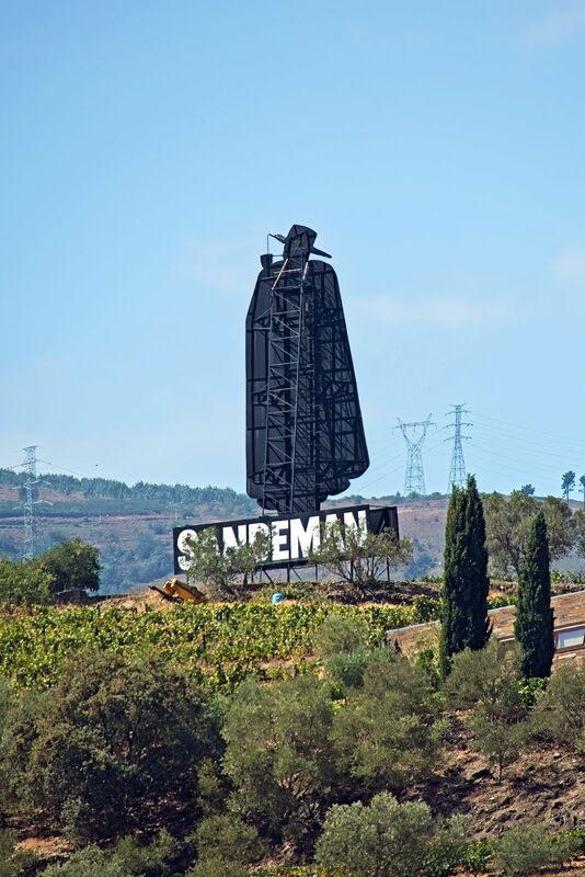 DC 22-0809-005.jpg :: Saga Douro River Cruise, Pinhao to Regua, Portugal: The iconic Don Sandeman logo overlooking terraced vineyards in the Douro Valley, Portugal. This large-scale silhouette is a famous landmark in the region, specifically near the town of Peso da Régua. The \