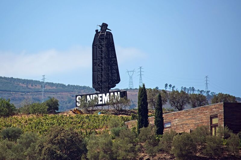 DC 22-0809-006.jpg :: Saga Douro River Cruise, Pinhao to Regua, Portugal: The iconic Don Sandeman logo overlooking terraced vineyards in the Douro Valley, Portugal. This large-scale silhouette is a famous landmark in the region, specifically near the town of Peso da Régua. The \