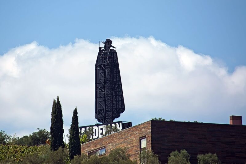 DC 22-0809-008.jpg :: Saga Douro River Cruise, Pinhao to Regua, Portugal: The iconic Don Sandeman logo overlooking terraced vineyards in the Douro Valley, Portugal. This large-scale silhouette is a famous landmark in the region, specifically near the town of Peso da Régua. The \