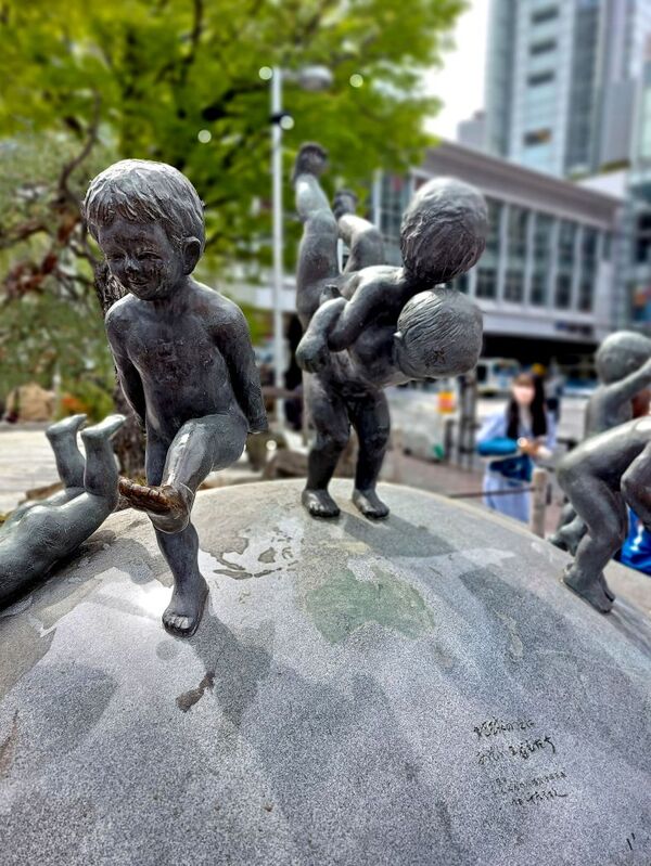 DC 23-0677-029.jpg :: Iglu Tour, Ultimate Japan & Cherry Blossom: Tokyo, Japan, A sculpture of young boys playing on the globe. Located outside Tokyo's Shibuya Station. Photo taken 31/03/2023