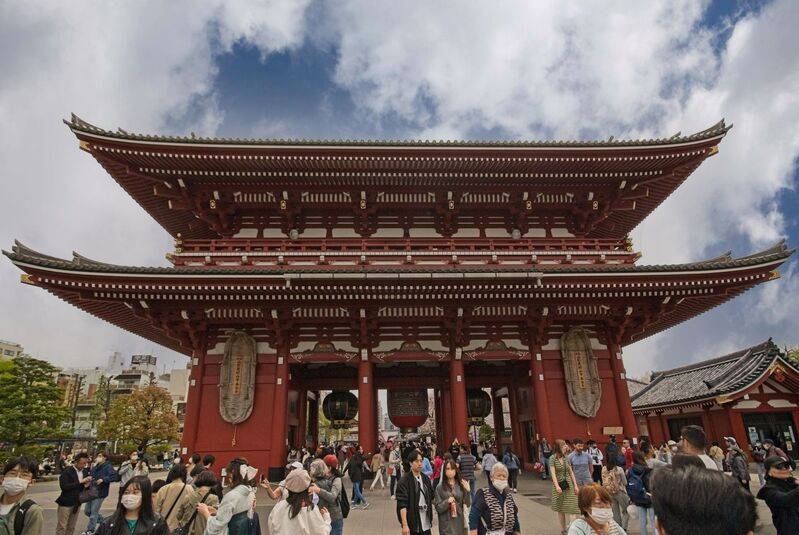 DC 23-0677-085.jpg :: Iglu Tour, Ultimate Japan & Cherry Blossom: Tokyo, Japan. Senso-ji, widely known as Asakusa Kannon Temple, is Tokyo’s oldest Buddhist temple. Located in Asakusa, one of Tokyo’s most lively and busy districts, Senso-ji is one of the most visited spiritual sites in the world. This bright and colourful temple attracts so many people from all over the world that at times it’s even hard to walk around the temple grounds. Senso-ji was founded almost one and half millennia ago, in 645. The legend says that in 628 two fishermen caught a statue of Kannon, the goddess of compassion, in the nearby Sumida River. They tried to get rid of it, but it kept coming back to them. Taking it as a sign, the head of the fishermen’s village erected Senso-ji in honor of Kannon. The temple holds the original Kannon statue; however it can never be seen by the public and is supposedly stored safely inside 3 boxes. P.s. Hozomon Gate – second gate. The second gate “Hozomon” leading to Senso-ji temple is also known as “Treasure-house gate”. The gate has a very unique look with it’s two floors. On the second floor, many of the temples treasures are stored, hence the name “Treasure-house gate”. The gate is decorated with three large lanterns and is protected by two Nio statues on the front face. The backside displays two large straw sandals. Like the Kaminarimon Gate this gate was also burned down and rebuilt on several occasions over the years. The current gate is from 1964 and is built in reinforced concrete and fire-resistant materials. At the back of the Hozomon gate you will most likely notice the two gigantic straw sandals hung up on the wall. Many questions pop into mind here. Firstly, why sandals? secondly why so big? Strange as this may seem today, sandals have been common offerings for temples when people came to pray. The explanation of the sandals apparently is that people would pray for their legs and lower body, as this part of the body was crucial for being able to work hence earn for food. The large size of the sandals is not common though. There appears to be a few different stories of why the sandals are there, but common for all the stories is that the huge sandals are offered to Senso-ji temple by the city of Maruyama in Yamagata, some 400km / 250mi from Tokyo. Every 10 years the city gets together and create a new pair of sandals which are donated to Senso-ji. Photo taken 31/03/2023
