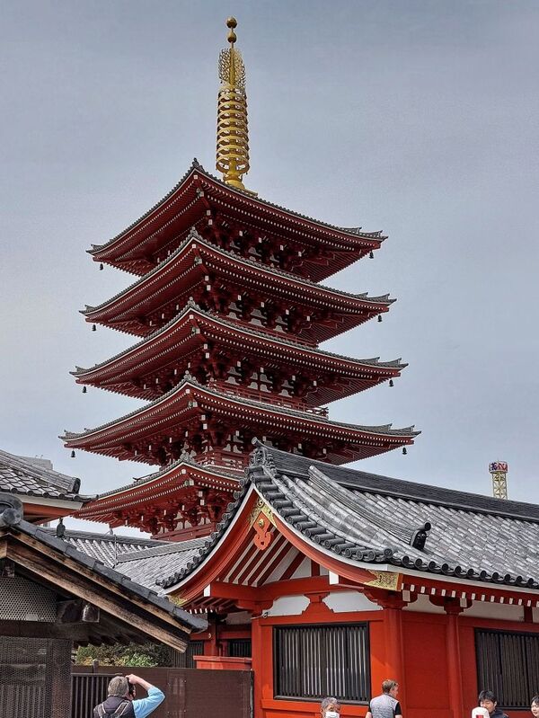 DC 23-0677-089.jpg :: Iglu Tour, Ultimate Japan & Cherry Blossom: Tokyo, Japan. Senso-ji, widely known as Asakusa Kannon Temple, is Tokyo’s oldest Buddhist temple. Located in Asakusa, one of Tokyo’s most lively and busy districts, Senso-ji is one of the most visited spiritual sites in the world. This bright and colourful temple attracts so many people from all over the world that at times it’s even hard to walk around the temple grounds. Senso-ji was founded almost one and half millennia ago, in 645. The legend says that in 628 two fishermen caught a statue of Kannon, the goddess of compassion, in the nearby Sumida River. They tried to get rid of it, but it kept coming back to them. Taking it as a sign, the head of the fishermen’s village erected Senso-ji in honour of Kannon. The temple holds the original Kannon statue; however, it can never be seen by the public and is supposedly stored safely inside 3 boxes. P.s. This five-stored pagoda inside the grounds of a popular tourist spot, Senso-ji Temple is a typical tower found in many Buddhist temples in Japan. Inside the pagoda, the remains of Buddha, the founder of Buddhism is placed. The original pagoda was constructed in 942. However, it has been successively lost by fire and subsequently reconstructed. The current pagoda was rebuilt in 1973 over the reinforced concrete base building and is 53.32 meters high. It becomes a popular sightseeing spot also for foreign visitors and draws attention. Photo taken 31/03/2023