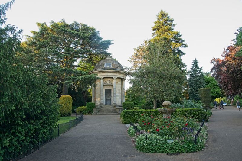 DC 24-0720-052.jpg :: Royal Leamington Spa: The Jephson Gardens are formal gardens, together with a grassed park, in the town of Leamington Spa, Warwickshire. The gardens, once a place for the wealthy to 'take the air' and 'be seen', are found in the centre of the town on the Parade, with the River Leam flowing to the south of them. One of the town's most popular tourist attractions, they have facilities such as cafes and floral displays. The gardens began as farmland which belonged to Edward Willes, a member of the Willes family who played an important part in the shaping of early Leamington. The original gardens, covering just under 10.5 acres (42,000 m2), were laid out in 1834 at the request of the landowner with free entry to anyone between 7 am and 10 am. For the remainder of the day the gardens were open only to paying customers and patrons of a nearby spa bath house. The Jephson Memorial. This Corinthian-style temple was added to the gardens in 1849 and inside it, there is a large marble statue of Doctor Henry Jephson. The memorial is a Grade II listed building. Memorial with statue of Dr Henry Jephson on plinth within circular, domed temple. 1848-1849. Temple by DG Squirill, statue by Peter Hollins. Photo taken 19/05/2024