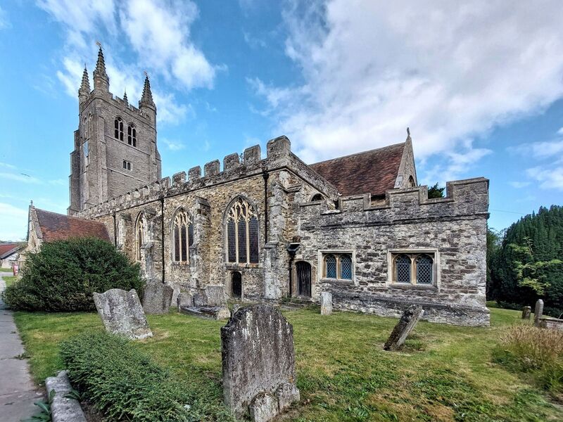 DC 24-0736-008.jpg :: Tenterden, Kent: St. Mildred's Church is an Anglican church located in Tenterden in the borough of Ashford in Kent. The church dates from about the 12th century and is Grade I heritage listed. The main tower of the church is 39.6 metres (130 feet) high and was constructed in 1461. It is dedicated to a prominent Anglo-Saxon saint, Saint Mildred, a 7th-century princess who served as the abbess of the nunnery at Minister-in-Thanet. The main tower of the church is built from Bethersden Marble, a limestone that contains thousands of brightly coloured shells. A graveyard is also present on the left-hand side of the church. Photo taken 04/09/2024