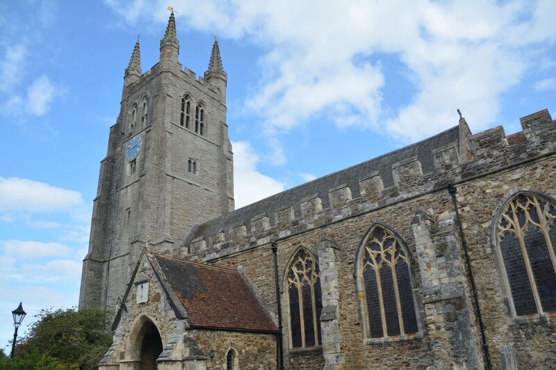 DC 24-0736-009a.jpg :: Tenterden, Kent: St. Mildred's Church is an Anglican church located in Tenterden in the borough of Ashford in Kent. The church dates from about the 12th century and is Grade I heritage listed. The main tower of the church is 39.6 metres (130 feet) high and was constructed in 1461. It is dedicated to a prominent Anglo-Saxon saint, Saint Mildred, a 7th-century princess who served as the abbess of the nunnery at Minister-in-Thanet. The main tower of the church is built from Bethersden Marble, a limestone that contains thousands of brightly coloured shells. A graveyard is also present on the left-hand side of the church. Photo taken 04/09/2024