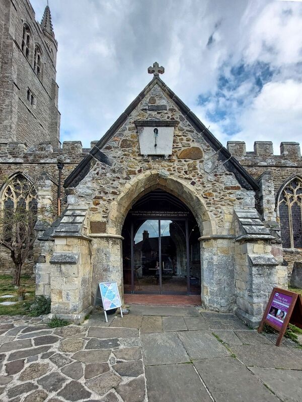 DC 24-0736-016.jpg :: Tenterden, Kent: St. Mildred's Church is an Anglican church located in Tenterden in the borough of Ashford in Kent. The church dates from about the 12th century and is Grade I heritage listed. The main tower of the church is 39.6 metres (130 feet) high and was constructed in 1461. It is dedicated to a prominent Anglo-Saxon saint, Saint Mildred, a 7th-century princess who served as the abbess of the nunnery at Minister-in-Thanet. The main tower of the church is built from Bethersden Marble, a limestone that contains thousands of brightly coloured shells. A graveyard is also present on the left-hand side of the church. Photo taken 04/09/2024