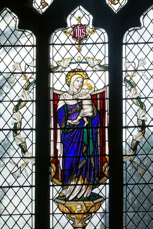 DC 24-0736-034.jpg :: Tenterden, Kent: St. Mildred's Church is an Anglican church located in Tenterden in the borough of Ashford in Kent. The church dates from about the 12th century and is Grade I heritage listed. The main tower of the church is 39.6 metres (130 feet) high and was constructed in 1461. It is dedicated to a prominent Anglo-Saxon saint, Saint Mildred, a 7th-century princess who served as the abbess of the nunnery at Minister-in-Thanet. The main tower of the church is built from Bethersden Marble, a limestone that contains thousands of brightly coloured shells. A graveyard is also present on the left-hand side of the church. Stained glass window. Madonna & Child - Christopher Webb of St Albans 1931. Photo taken 04/09/2024