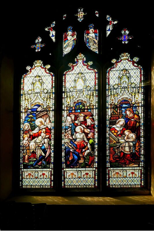 DC 24-0736-035.jpg :: Tenterden, Kent: St. Mildred's Church is an Anglican church located in Tenterden in the borough of Ashford in Kent. The church dates from about the 12th century and is Grade I heritage listed. The main tower of the church is 39.6 metres (130 feet) high and was constructed in 1461. It is dedicated to a prominent Anglo-Saxon saint, Saint Mildred, a 7th-century princess who served as the abbess of the nunnery at Minister-in-Thanet. The main tower of the church is built from Bethersden Marble, a limestone that contains thousands of brightly coloured shells. A graveyard is also present on the left-hand side of the church. Stained glass window. Photo taken 04/09/2024