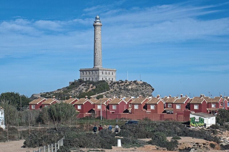 DC 24-0764-033.jpg :: Cabo de Palos, La Manga, Spain: The lighthouse of Cabo de Palos is located on an approximately 600 meters-wide small peninsula in the municipality of Cartagena. Back in its time, there was a watchtower where the lighthouse is currently located. The simple structure is defined by its surveillance function as well as the lighthouse-keepers school which was housed in its base. The construction started in 1863 and the lighthouse was first lit on the 31st January, 1865. The building rises 30 meters above sea level, according to Leonardo de Tejada's project. Ashlar stones brought in from a quarry located in the town of Sabinar were used as building material. It has a prism-shaped base of 20 meters on each side and 14 meters high with rusticated edges. In the middle of the base, above an octagonal shaped pedestal rises the 54 meters high tower. It adopts the form of a Tuscan order column, and its capital consists of various corbels that hold up a circular cornice with an openwork parapet in a shape of a balustrade. Above, there is a cylindrical tower where the lantern is built in. Nowadays, it has a beacon with a range of 24 miles. Photo taken 06/12/2024