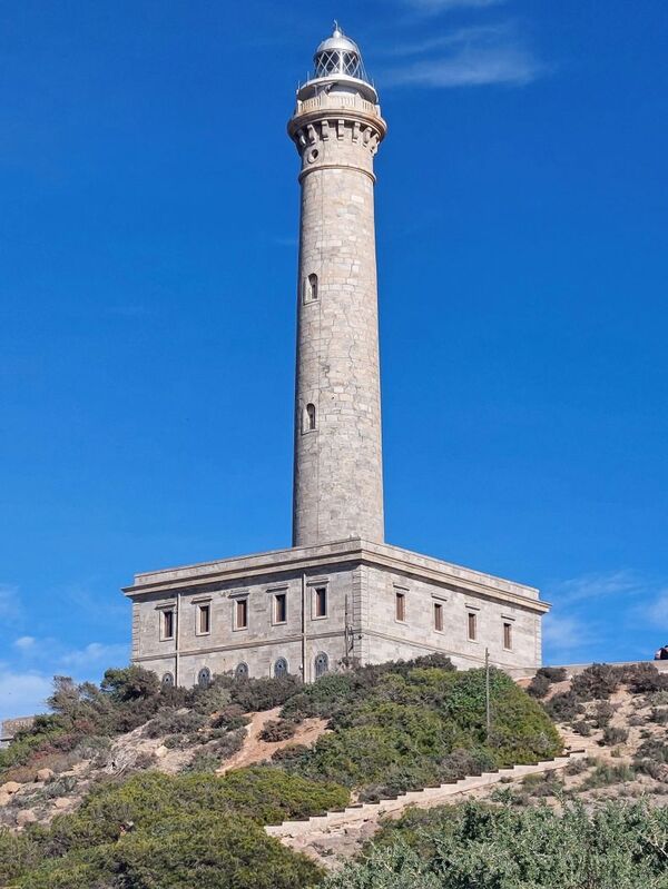 DC 24-0764-039.jpg :: Cabo de Palos, La Manga, Spain: The lighthouse of Cabo de Palos is located on an approximately 600 meters-wide small peninsula in the municipality of Cartagena. Back in its time, there was a watchtower where the lighthouse is currently located. The simple structure is defined by its surveillance function as well as the lighthouse-keepers school which was housed in its base. The construction started in 1863 and the lighthouse was first lit on the 31st January, 1865. The building rises 30 meters above sea level, according to Leonardo de Tejada's project. Ashlar stones brought in from a quarry located in the town of Sabinar were used as building material. It has a prism-shaped base of 20 meters on each side and 14 meters high with rusticated edges. In the middle of the base, above an octagonal shaped pedestal rises the 54 meters high tower. It adopts the form of a Tuscan order column, and its capital consists of various corbels that hold up a circular cornice with an openwork parapet in a shape of a balustrade. Above, there is a cylindrical tower where the lantern is built in. Nowadays, it has a beacon with a range of 24 miles. Photo taken 06/12/2024