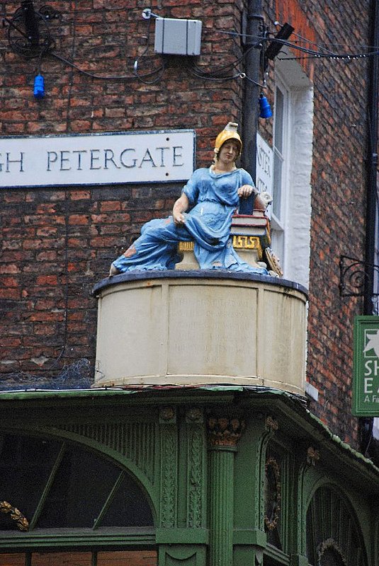 DC 12-0277-014.jpg :: High Petergate, York: Petergate was the Via Principa, or main cross street of  Eboracum (the Roman name for York). The statue of Minerva, Goddess of Wisdom, sitting with an owl and a pile of books, a reminder of the days when this was the street of bookbinders and booksellers. This point is also the main road intersection of Roman York and the entrance to the Principia - the Roman military headquarters. 24/01/2012
