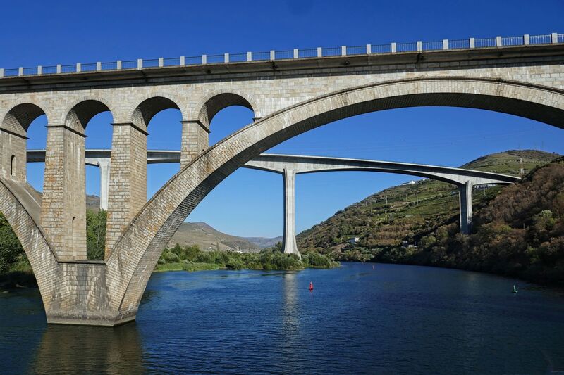 DC 22-0789-017.jpg :: Saga Douro River Cruise, Regua Lamego to Pinhao, River Douro: The Régua Railway Bridge at Peso da Régua, also known as the Régua Road Bridge, because this is its current use, is a bridge over the Douro River, connecting the municipalities of Peso da Régua, on the right bank, and Lamego, on the left bank. Built in 1934 within the scope of the Lamego Line, it was adapted to road use since that railway project had not been completed. The bridge was built by the National Railway Company, with the project being prepared by the engineer Avelar Ruas, and the work conducted by the engineer Maçãs Fernandes. Photo taken 30/08/2022.