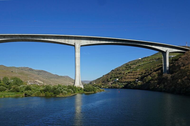 DC 22-0789-019.jpg :: Saga Douro River Cruise, Regua Lamego to Pinhao, River Douro: The Ponte Miguel Torga is a modern concrete viaduct carrying the A-24 highway across the Douro River near Peso da Régua, and is named after the renowned 20th-century Portuguese writer Miguel Torga. The 900-meter-long bridge features a continuous prestressed concrete box girder deck and a large 180-meter span over the river. Photo taken 30/08/2022.