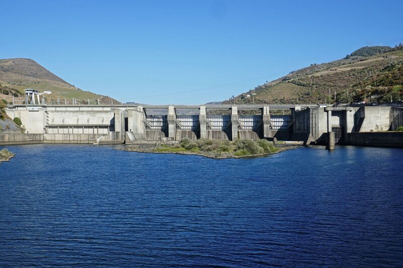 DC 22-0789-030.jpg :: Saga Douro River Cruise, Regua Lamego to Pinhao, River Douro: Régua Dam (Portuguese: Barragem da Régua) is a concrete gravity dam on the Douro, where the river forms the border line between the districts of Vila Real and Viseu. It is located in the municipality Peso da Régua, in Vila Real District. Construction of the dam began in 1965. The dam was completed in 1973. It is owned by Companhia Portuguesa de Produção de Electricidade (CPPE). Photo taken 30/08/2022.