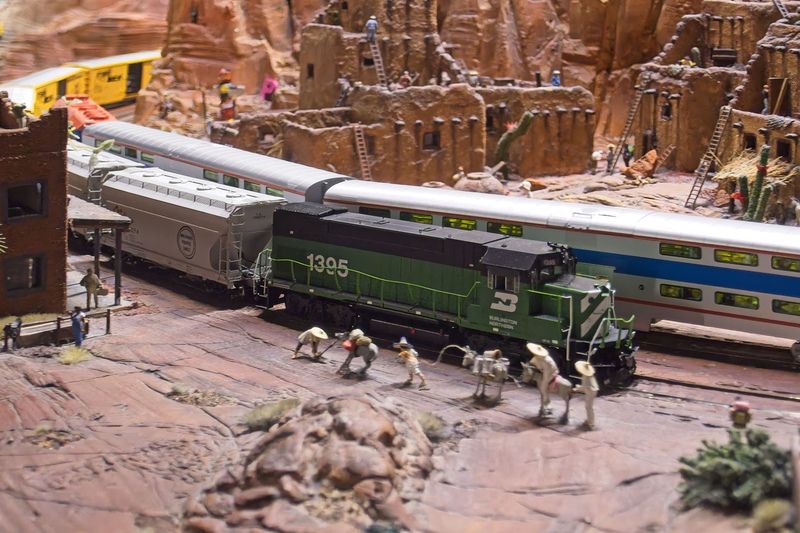 DC 25-0767-081.jpg :: Miniatur Wunderland Hamburg, Germany: The Miniatur Wunderland is, according to Guinness World Records, the largest model railway system in the world. It is located at the historic Speicherstadt in Hamburg and is one of the most popular and most visited sights in Germany. The exhibition includes around 1,230 digitally controlled trains with more than 12,000 wagons. The Wonderland is also designed with around 4,300 houses and bridges, more than 10,000 vehicles – of which around 350 drive independently on the installation – 47 airplanes and around 290,000 figures. The system features a recurring day-night lighting cycle and almost 500,000 built-in LED lights. Of the 7,000 m2 (75,347 sq ft) of floorspace, the models occupy 1,545 m2 (16,630 sq ft). P.s. Part of the USA section of the exhibition. Trains passing through a Pueblo Settlement in Arizona. Photo taken 20/01/2025