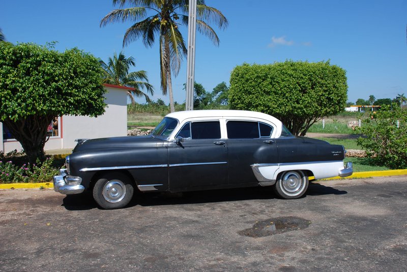 DC 11-0240-014.jpg :: 2011 - Cuban Classic Cars - 1954 Chrysler Windsor Deluxe outside resturante at La Aguada. These American dream cars are common all over Cuba. There is no suggestion that the car is in its original condition as these cars are kept running using all sorts or suitable spares and non original components. The chances are the engines are either Japanese or Russian. Reg. No. MDF 409 on a yellow Cuban plate. 29/05/2011  
