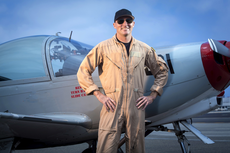Fighter Pilot smiling at camera standing next to prop plane 001.jpg :: Fighter pilot standing next to Marchetti SIAI SF260 fighter propeller airplane  - Horizontal