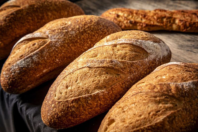 Loaves of bread on wood table with baguette in background 002.jpg