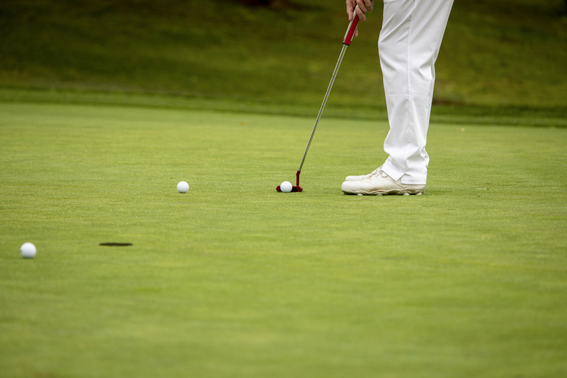 Male Golfer putting on green in white pants.jpg :: Male Golfer putting on green wearing white pants