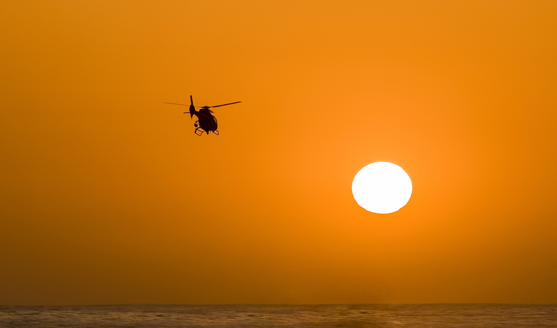 Sihouette of helicopter headed toward setting sun 0001.jpg :: Sihouette of helicopter headed toward setting sun over water. Graphic image with negative space