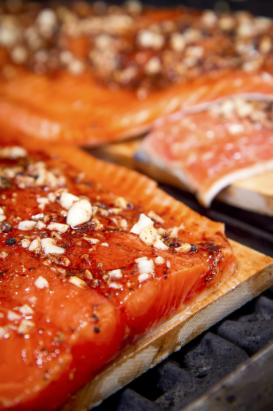 close up of Salmon with garlic clove rub on cedar planks for cooking on BBQ 001.jpg :: Salmon with garlic glaze on bar-b-que grill with salmon cooking in background