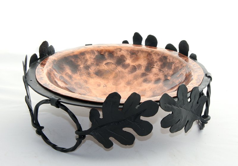 Bowl w-Copper Dish.jpg :: $150.00 - Use this hand-shaped copper bowl in the kitchen for fruit or veggies or in any other room as an accent piece. It takes hundreds of hammer blows to beat the bowl into shape and each bears unique texture marks. The bowl sits in a forged ring made up of entwined leaves and circles and lifts out for cleaning. The overall piece is approx 12\