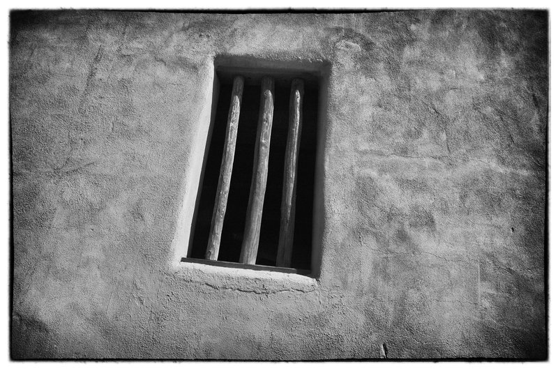 Santa Fe NM.jpg :: Side lighting on a parking garage in Santa Fe, New Mexico in the waning hours of day provides an opportunity to capture  form, depth and texture, reminiscent of an old western jail. 