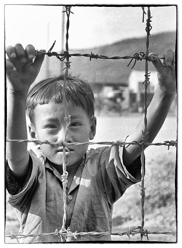 A Boy and Barb Wire.jpg :: Curiosity and begging go together and is practiced around the perimeters of all military bases in Vietnam. I personally felt sorry for these kids who really have no idea that there is warfare in their country or who and why we were there. Interestingly  the American  was often times referred to as a Doughboy.