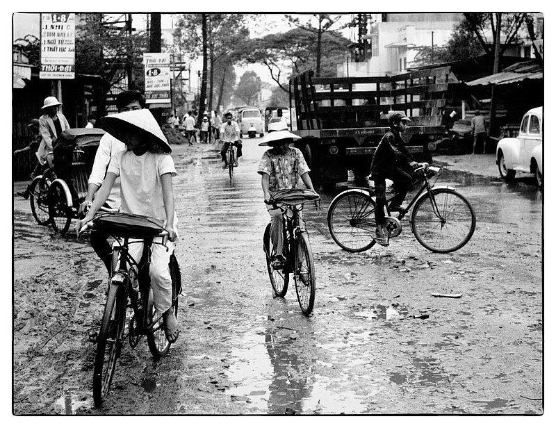 After a Monsoon.jpg :: Street scene of Vietnamese people navigating the water and mud on bicycles after an afternoon Monsoon. Was always amazed at how they escaped getting covered in mud.