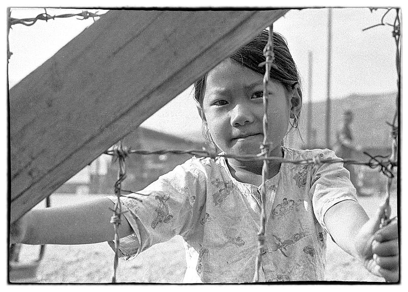 Barbed Wire.jpg :: As stated previously many Vietnamese children liked to hang out around the periphery of our Military Bases. For the most part they are quiet and as usual Soldiers will pass candy or other food stuff to them.