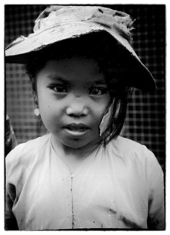 Child and hat.jpg :: Children in Vietnam are naturally curious, while I was  filming they would appear out of nowhere just to watch. Children were used by 'Charlie' as instruments of war often times being wired with explosives. The VC knew of  the American soldiers kindness to children, probably where she got the hat.