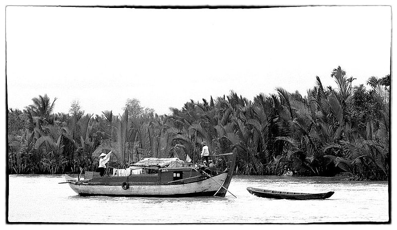 Delta life.jpg :: Sometimes, the seemingly innocent looking, working boats are not what they seem to be. In an instant the boat can become an arsenal of hell on water. Traversing the rivers requires constant observation and awareness.