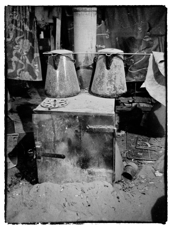 Old Wood stove.jpg :: I quickly notice the old wood stove with ash surrounding the base, scattered along the floor along with other clutter, it is instrumental in his survival, serveing him well over the years, it heats his water for tea, cooks his food and most of all provides warmth in the cool evenings and the winter cold of Maryland.  Im not certian how safe the box stove is but I choose not to ask.
