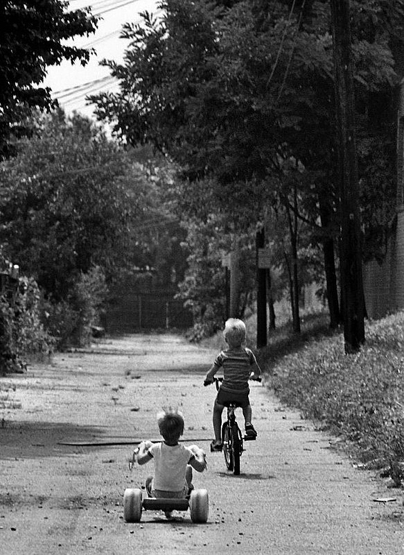 The Ride.jpg :: Two brothers both learning to ride. Hours of practice on a little dirt passageway behind their home and suddenly success.