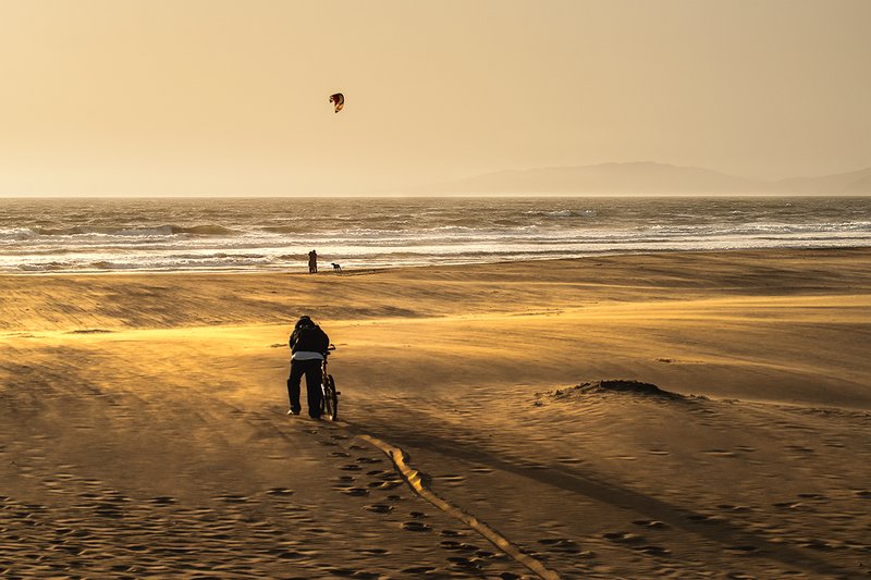 Windward.jpg :: A biker fights the wind at sunset along the San Francisco coastline to reach the surf.