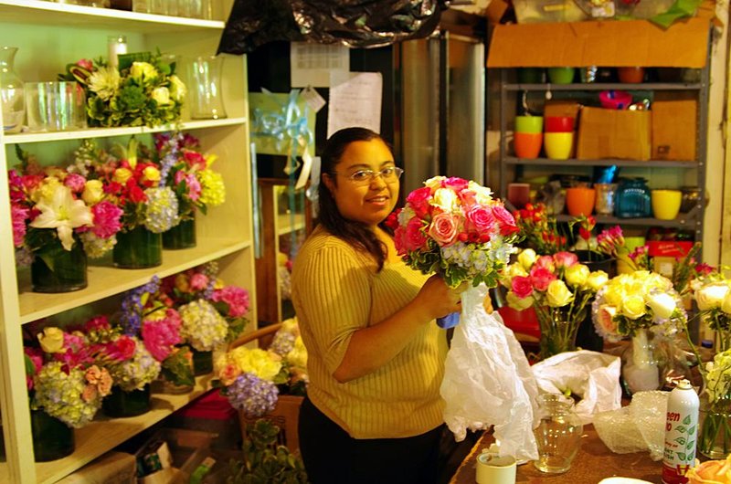 Assiciate designer Eric Rodriguez prepares a Maid of Honor bouquet for the ride to the church.jpg