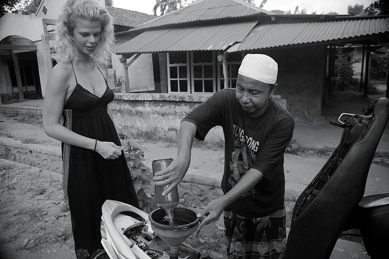 IMG_7908 84.jpg :: A Swedish girl gets gas put into her motorbike by an Indonesian man on Lombok, Indonesia.