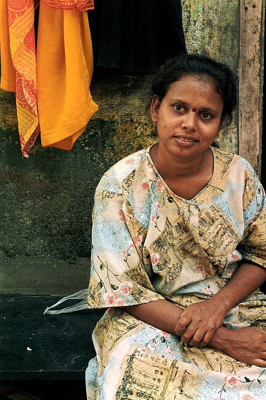 sittingindianwoman2.jpg :: A young Indian woman next to her home in Mumbai, India.