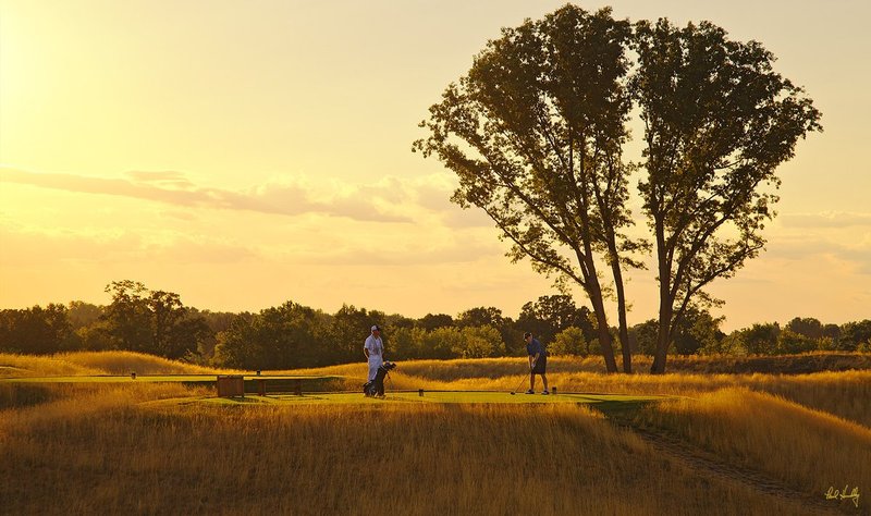E101--0080  V1  1500px  SS - with signature.jpg :: A player and his caddy on the 18th tee as daylight fades at Erin Hills, a daily fee golf course in Erin, Wisconsin.  Erin Hills was designed by Hurdzan/Fry and Ron Whitten and built by Landscapes Unlimited, LLC, and has been choosen to host the 2011 US Amateur Chanpionship and the 2017 US Open Championship.  Photo by Paul Hundley; taken in July, 2012.