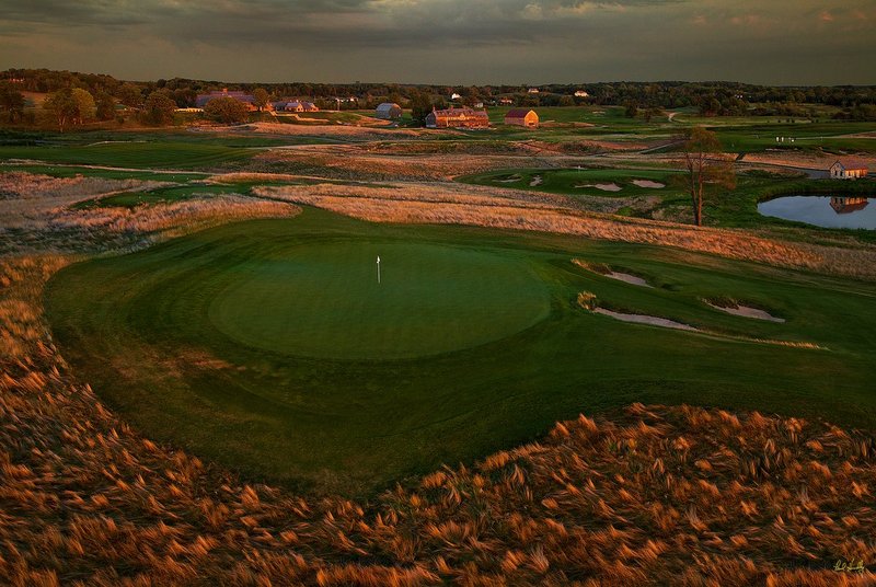 E101--0863  V1  1500px  SS - with signature.jpg :: The par four 8th green (foreground) with the par 3 9th hole and 18th green above and The Lodge and Village Clubhouse in the distance at Erin Hills, a daily fee golf course in Erin, Wisconsin.  Erin Hills was designed by Hurdzan/Fry and Ron Whitten and built by Landscapes Unlimited, LLC, and has been choosen to host the 2011 US Amateur Chanpionship and the 2017 US Open Championship.  Photo by Paul Hundley; taken in September, 2012.