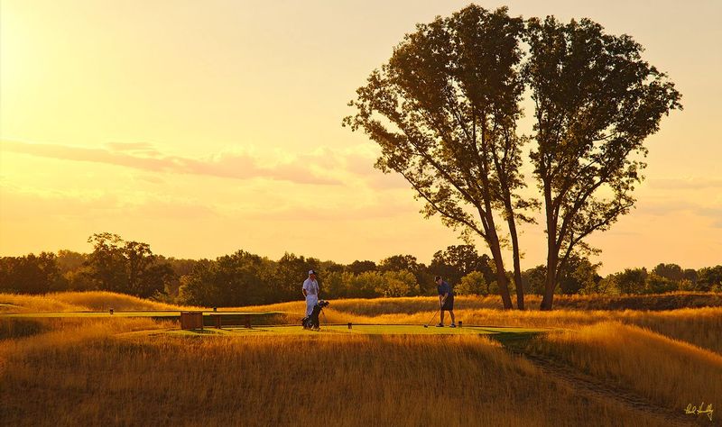E101--0080  V1  1500px  SS - with signature1.jpg :: A player and his caddy on the 18th tee as daylight fades at Erin Hills, a daily fee golf course in Erin, Wisconsin.  Erin Hills was designed by Hurdzan/Fry and Ron Whitten and built by Landscapes Unlimited, LLC, and has been choosen to host the 2011 US Amateur Chanpionship and the 2017 US Open Championship.  Photo by Paul Hundley; taken in July, 2012.