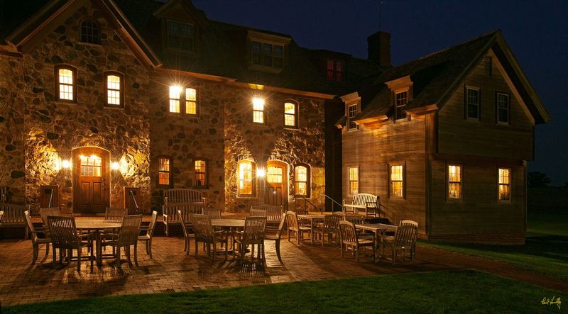 E101--Lodge 002  V1  1500px  SS - with signature1.jpg :: Exterior view of the courtyard at night outside The Lodge at Erin Hills, a daily fee golf course in Erin, Wisconsin.  Erin Hills was designed by Hurdzan/Fry and Ron Whitten and built by Landscapes Unlimited, LLC, and has been choosen to host the 2011 US Amateur Chanpionship and the 2017 US Open Championship.  Photo by Paul Hundley; taken in September, 2012.