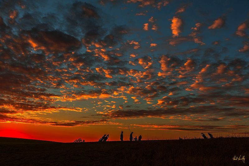 E101--Players 069  V1  1200px  SS  with signature.jpg :: The sun sets as players finish on the par five closing hole at Erin Hills, a daily fee destination golf course and resort in Erin, Wisconsin and site of the 2017 US Open Championship.  The course was designed by Hurdzan/Fry and Ron Whitten and built by Landscapes Unlimited, LLC.  It opened for play in 2006 and has already hosted the 2011 US Amateur Chanpionship and the 2008 Women's Amateur Public Links.  Photograph and copyright by Paul Hundley, September, 2014.