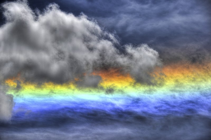 GBL-UTM-16.jpg :: A circumhorizontal arc, also known as a fire rainbow, is an optical phenomenon that belongs to the family of ice halos formed by the refraction of sun- or moonlight in plate-shaped ice crystals suspended in the atmosphere, typically in cirrus or cirrostratus clouds. In its full form, the arc has the appearance of a large, brightly spectrum-coloured band (red being the topmost colour) running parallel to the horizon, located far below the Sun or Moon. The distance between the arc and the Sun or Moon is twice as far as the common 22-degree halo. Often, when the halo-forming cloud is small or patchy, only fragments of the arc are seen. As with all halos, it can be caused by the Sun as well as (but much more rarely) the Moon. Other currently accepted names for the circumhorizontal arc are circumhorizon arc or lower symmetric 46 degree plate arc. The misleading term \